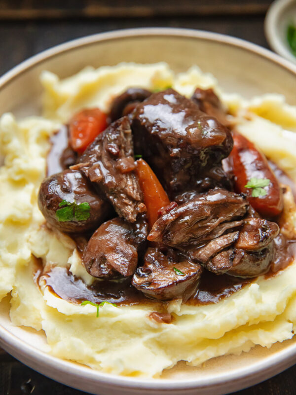 Close up of short rib bourguignon on mashed potatoes in a bowl