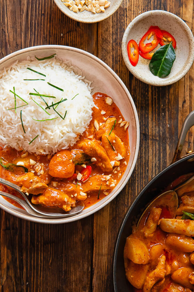 a serving of curry with rice in a bowl on a wooden background