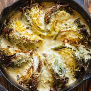 Cast iron skilled with cabbage wedges arranged in a fan and covered by a creamy sauce.