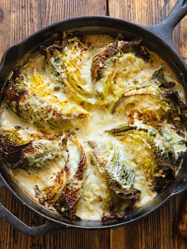 Cast iron skilled with cabbage wedges arranged in a fan and covered by a creamy sauce.