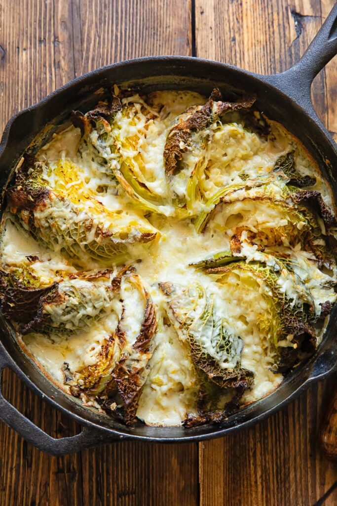 Cast iron skilled with cabbage wedges arranged in a fan and covered by a creamy sauce.