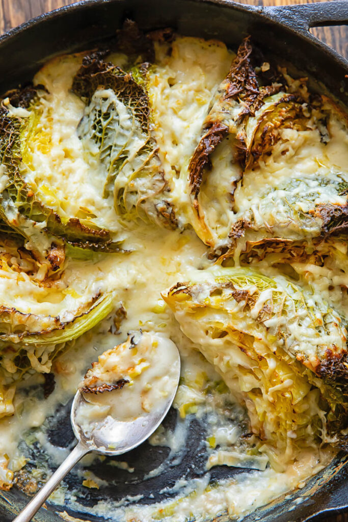 Close up of a skilled with wedges of savoy cabbage in a creamy sauce.