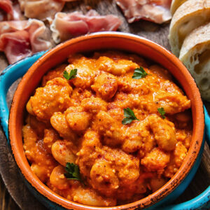 Close up of butter beans in Romesco sauce in a small serving dish
