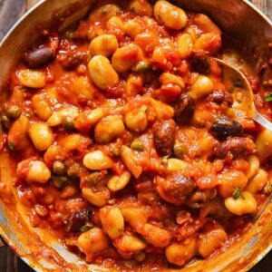 Top down shot of butter beans puttanesca in a pan