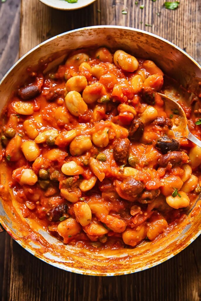 Top down shot of butter beans puttanesca in a pan