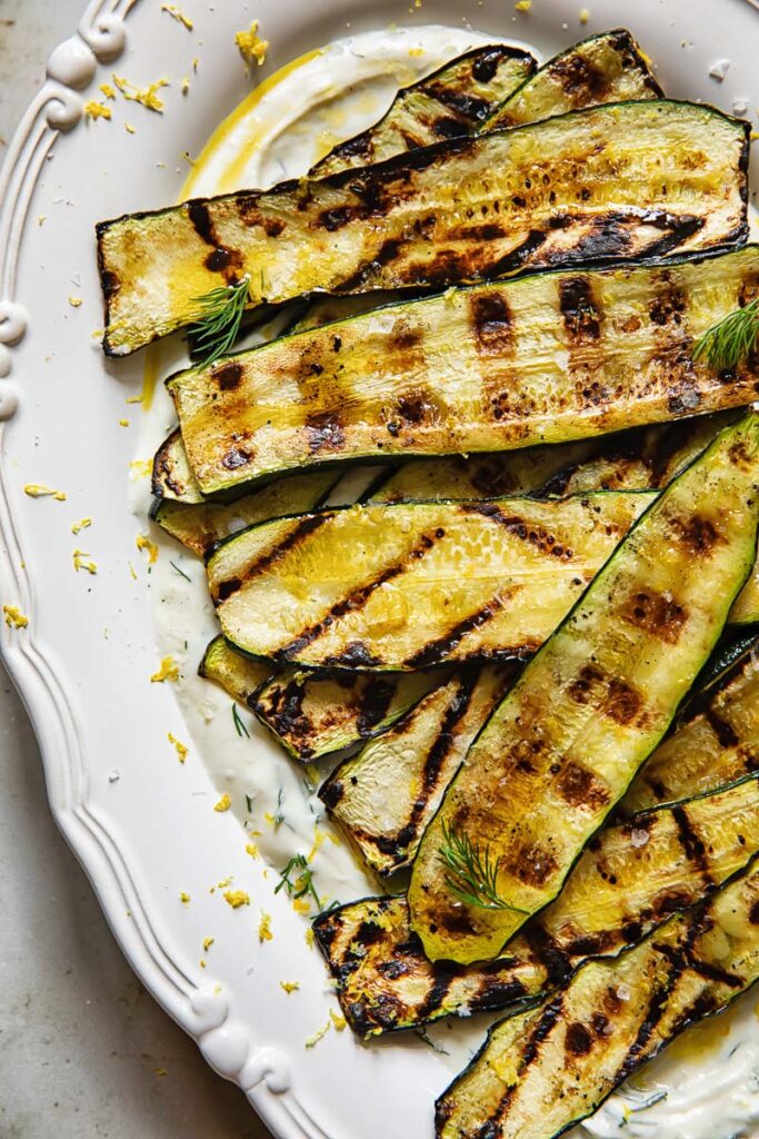 vertical shot of grilled zucchini on a bed of whipped feta