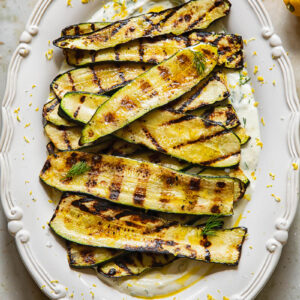 vertical shot of grilled zucchini on a bed of whipped feta