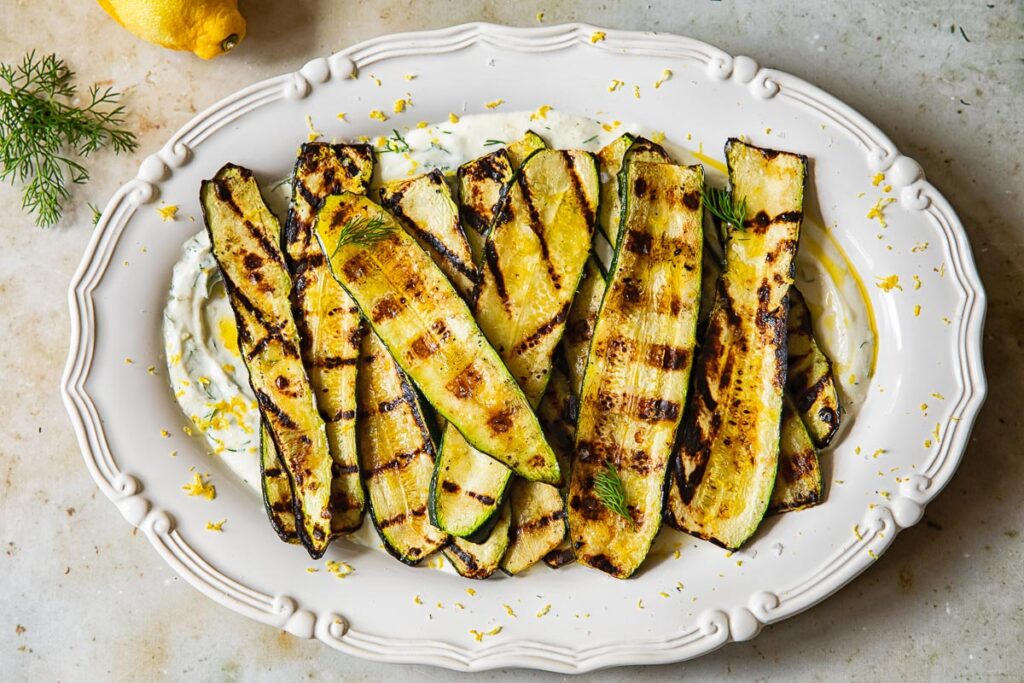 horizontal shot of grilled zucchini on a bed of whipped feta