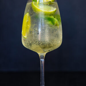 vertical photo of white wine glass with limoncello spritz