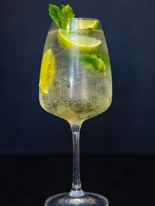 vertical photo of white wine glass with limoncello spritz