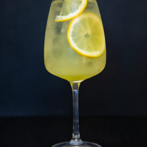 vertical shot of limoncello spritz cocktail against black backdrop