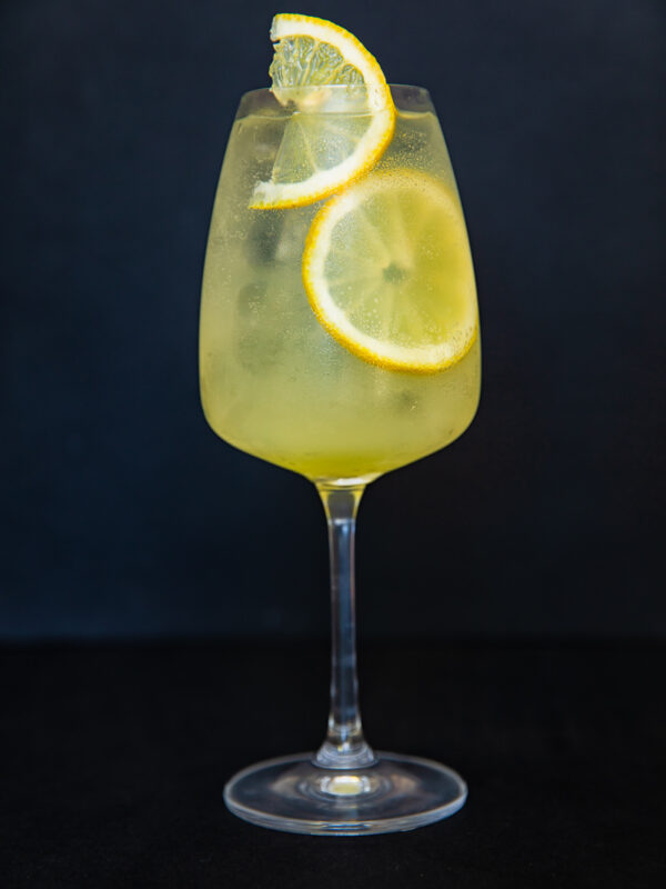 vertical shot of limoncello spritz cocktail against black backdrop