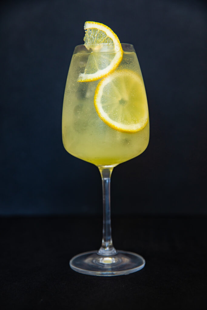 vertical shot of limoncello spritz cocktail against black backdrop
