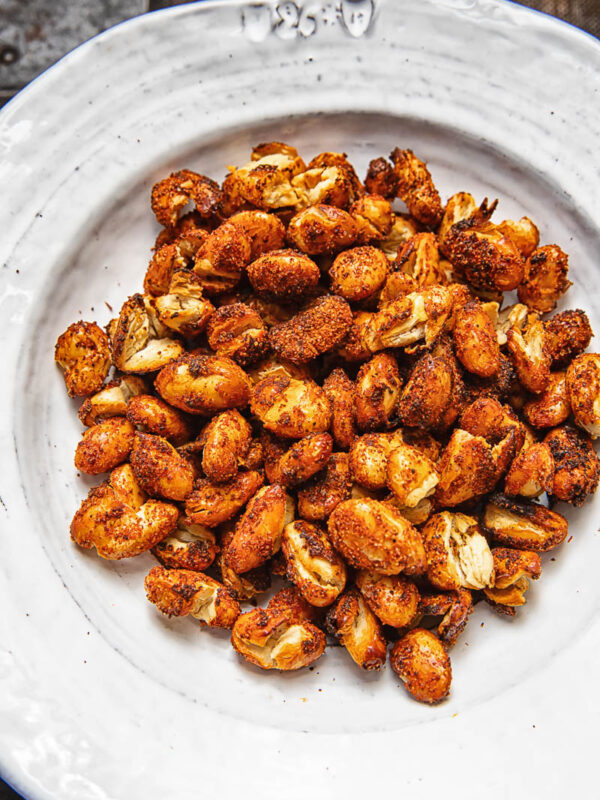 A pile of spiced butter beans on a white plate against a wood background.