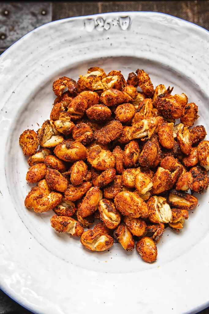 A pile of spiced butter beans on a white plate against a wood background.