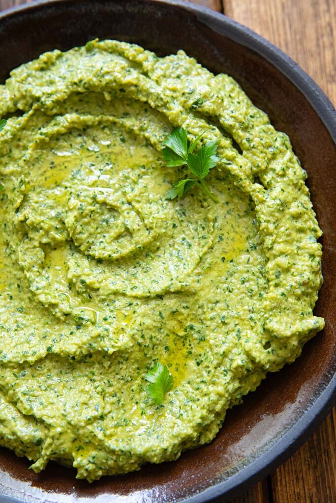 Close up image of green sauce on a dark plate and background.