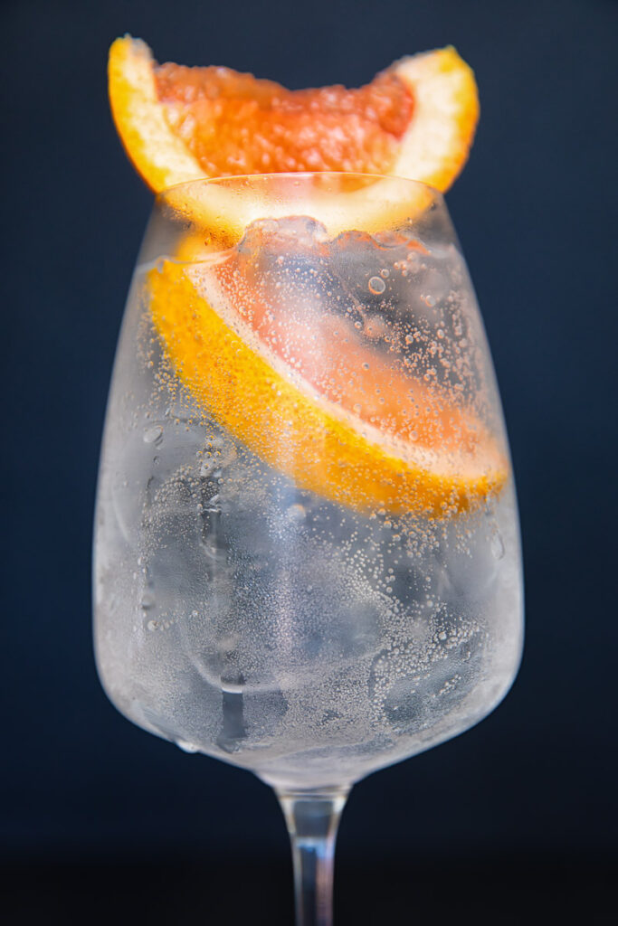 Close up of a wine glass with the spritz with two prominent slices of grapefruit on top.