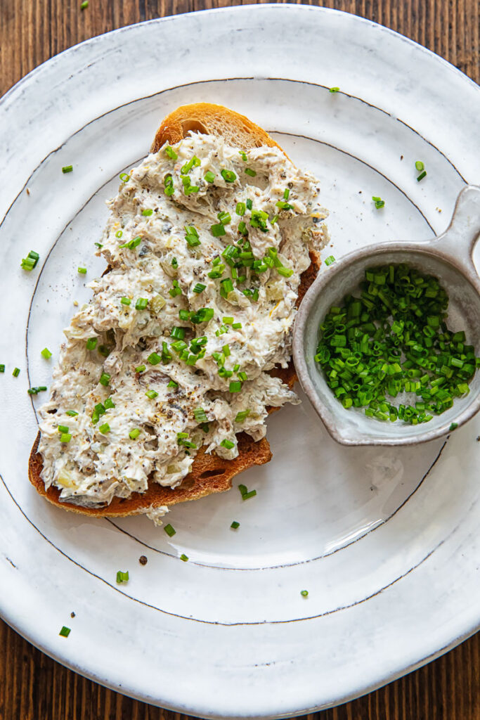 Toast on a white plate with a creamy topping plus chopped chives