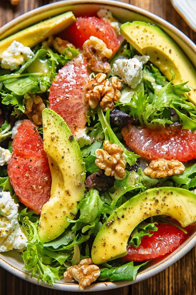 Close up of a bowl of autumn salad with avocado, walnuts and grapefruit slices.